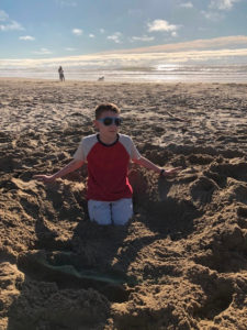 Teen buried his legs in the sand on the Oregon Coast