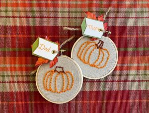 Two small embroidery hoops with canvas and embroidered pumpkins and name tags for mom and dad.