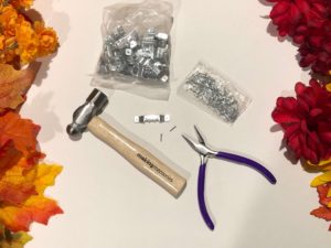 Hammer, needle nose pliers, sawtooth hanger, and tiny nails for attaching hardware to a frame