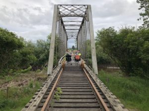Family riding a pedal cart across the historic 1901 truss bridge in Tillamook, OR