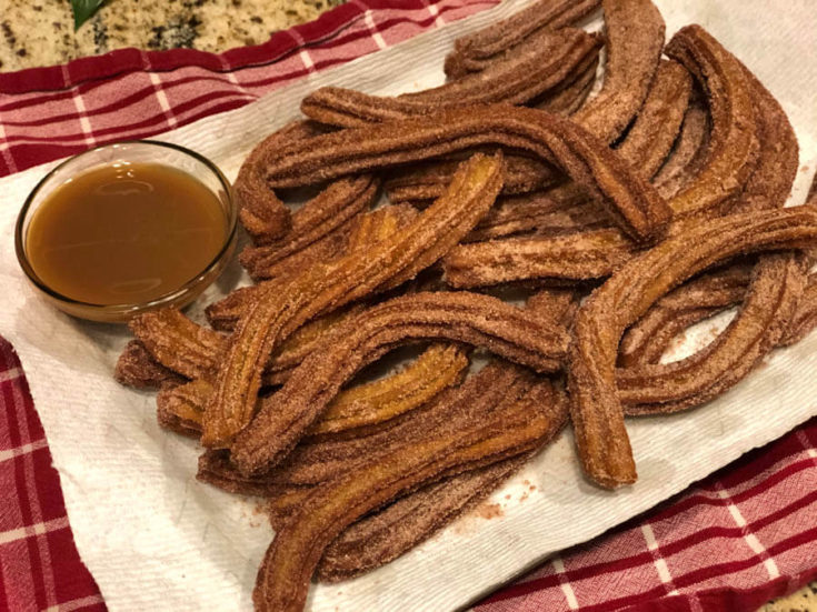 A tray of Pumpkin Spice Churros coated in pumpkin spiced sugar served with caramel sauce