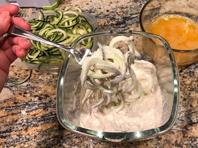 Spiralized zucchini getting tossed in flour