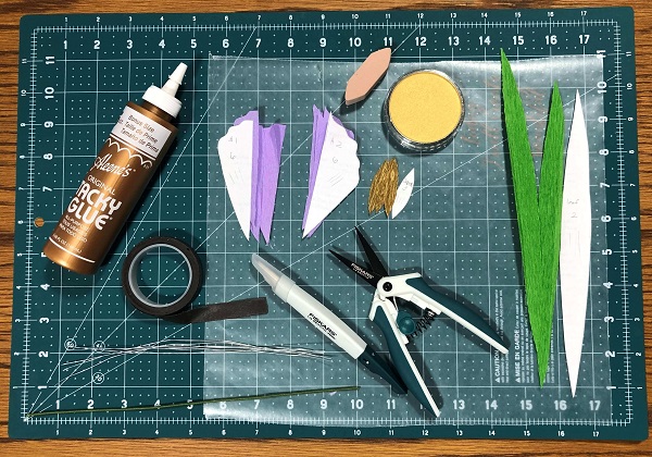 supplies for making crepe paper flowers including glue, crepe paper, pattern pieces, scissors, wire, panpastels, and floral tape
