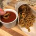 Dipping breaded zucchini curly fries into marinara sauce